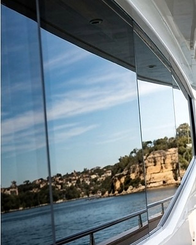 Sandstone cliffs and sky mirrored in the tinted glass of a saloon window